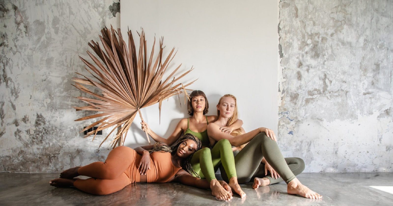 Drei Frauen in Yoga-Hosen und Leggings posieren für ein Foto