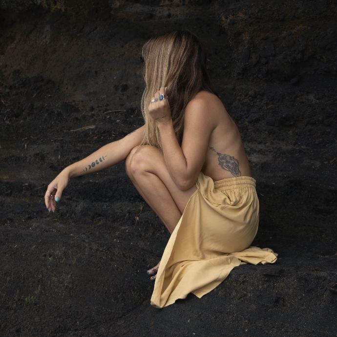 Frau im gelben Kleid sitzt auf einem Felsen